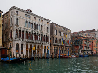 Fototapeta na wymiar Facades of weathered buildings with windows on street of Venice city near canal water in daylight