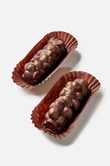 Two dark chocolate bars with hazelnuts in paper wrappers