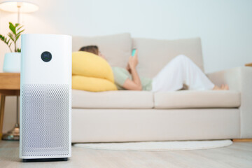 Air Purifier with woman relax and use smartphone on sofa. Purification system for filter and...