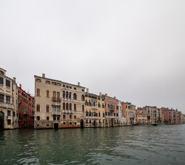 Facades of weathered buildings with windows on street of Venice city near canal water in daylight