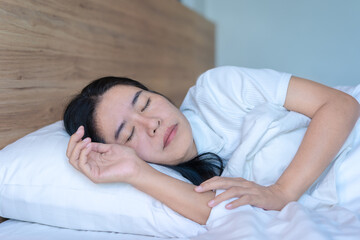 Calm Asian woman sleeping and sweet dreams lying on a comfortable bed in a cozy bedroom in the morning feeling relaxed..Way of life, relaxation, good health, and simple living. Health care concept.