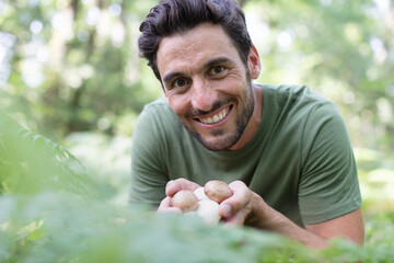 cheerful man gathering mushrooms in the woods - Powered by Adobe