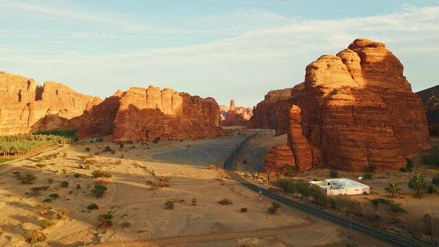 Asphalt road with orange rocks and yellow sand on sunset. Al Ula, Saudi Arabia - Aerial drone view.