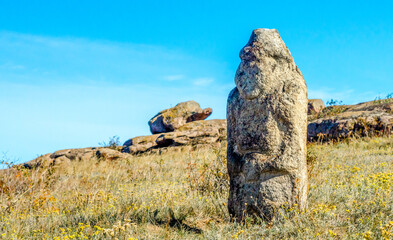 ancient stone idol in a field amidst stones
