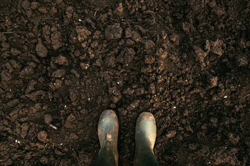 Top view of dirty rubber boots on soil ground