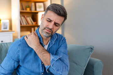 Young man with shoulder pain. male holding his painful shoulder. man hand holding his shoulder suffering from shoulder pain suffering from pain in hand at home.