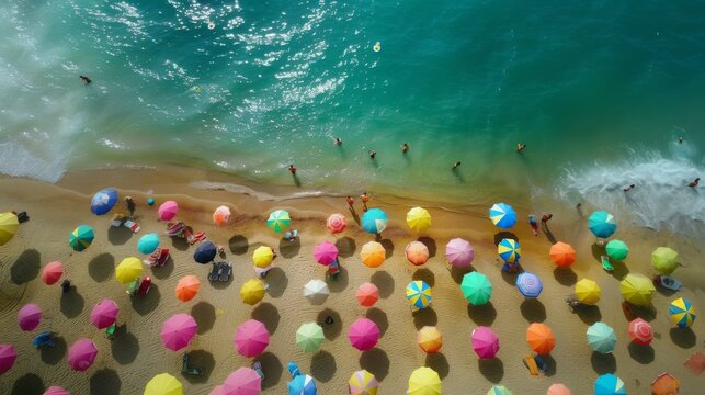 Top-down shot capturing a lively beach atmosphere with people under colorful umbrellas by the sea.
