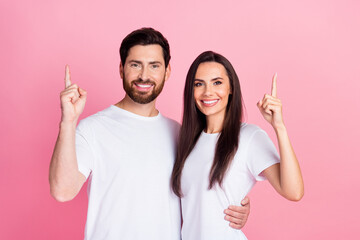 Photo portrait of lovely young couple hugging point up empty space wear trendy white garment isolated on pink color background