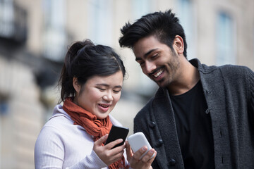 Happy Asian friends looking at smartphone's.