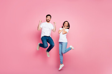Fototapeta na wymiar Full size photo of attractive young couple jumping raise fists celebrate wear trendy white outfit isolated on pink color background