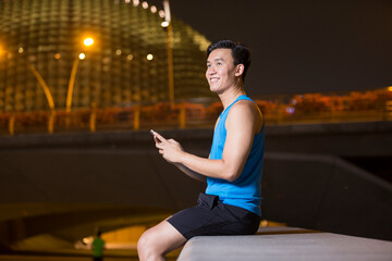 Fototapeta premium Sporty Asian man, using his smart phone.