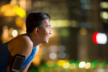 Fototapeta premium Sporty Asian man outdoors in urban city at night