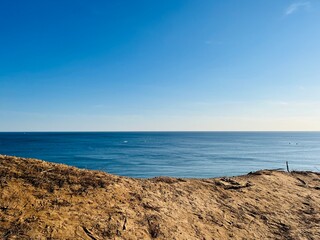 Fototapeta na wymiar Sandstone rocky coast, blue ocean horizon, clear sky, ocean bay