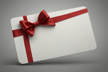 Close up of a gift card with red ribbon bow on gray background