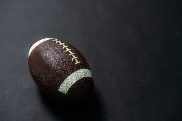 American football in a studio shot. The ball is over a black background that is lightly illuminated.