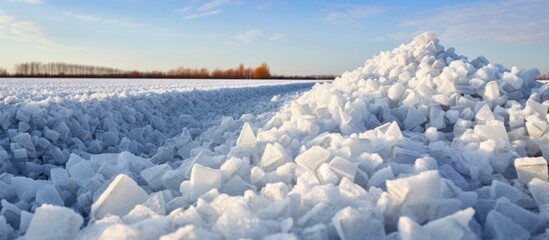 A large pile of ice is sitting in the middle of a field, creating a stunning display of salt crystals against the backdrop of a farmers field. The ice pile stands out prominently, contrasting with the