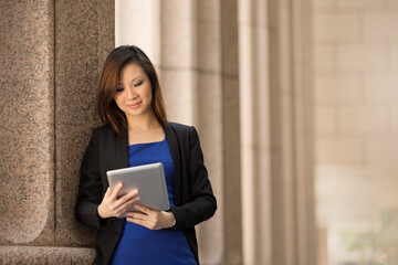 Asian businesswoman outside Colonial building using tablet.