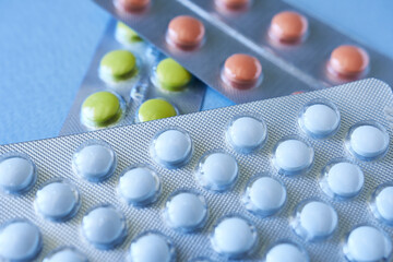 Tablets in blister packs on blue background. Focus on foreground, soft bokeh.