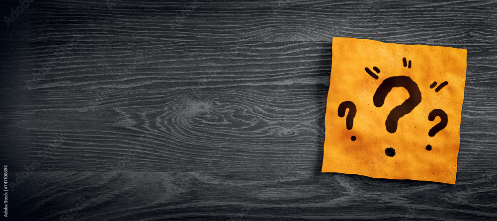 Poster Close up of orange note paper with question marks on wide dark wooden desktop with mock up place. Questions and answers concept. 3D Rendering.