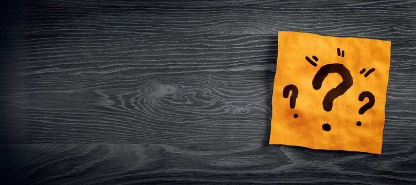 Close up of orange note paper with question marks on wide dark wooden desktop with mock up place. Questions and answers concept. 3D Rendering.