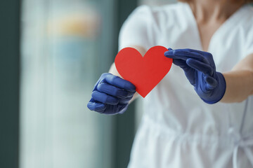 Female doctor is holding heart shaped paper, conception of cardiology