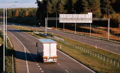White semi-trailer trucks on the highway driving in the left lane. Commercial vehicle for shipping...