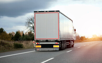 White semi-trailer trucks on the highway driving in the left lane. Commercial vehicle for shipping and post delivery. Shipping of the goods on land door-to-door	