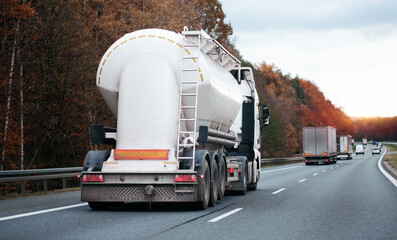 Petrol truck on highway hauling fossil oil refinery products. Fuel delivery transportation. Aviation fuel transportation. Compressed gas carrier truck rear view on a highway. Dairy products carrier	