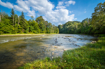 Shallow river with stones, San river, San valley in Bieszczady mountains, low mountain ridges covered with forest, late summer, San Valley Landscape Park