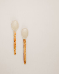 Two Unique Ceramic Spoons with Wooden Handles on a White Surface