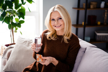 Photo of adorable cheerful lovely woman holding glass fresh water taking pills immunity health care home indoors