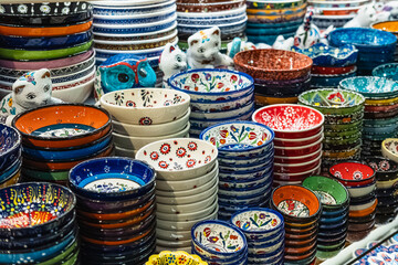 Variety of colorfully hand painted plates for sale at a market. Decorative ceramic plates on a shelf of a store - obrazy, fototapety, plakaty