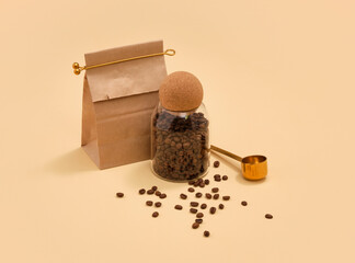 Coffee beans in a glass jar and paper bag. Golden coffee spoon.