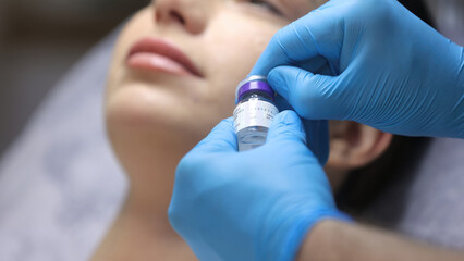 Close-up of a Caucasian, young brunette undergoing cosmetic beauty injections. The cosmetologist...