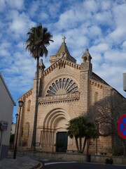 Historic Son Carrio church in Mallorca, under a cloudy blue sky