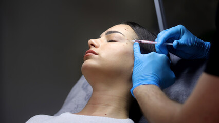 Close-up of a woman's face undergoing cosmetic injections. Wrinkles as a manifestation of skin...