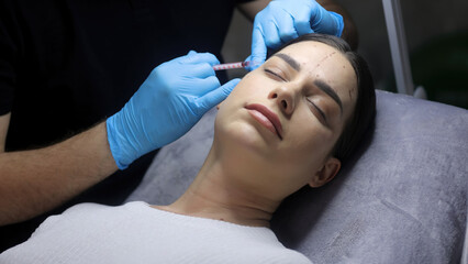 Close-up of a woman's face undergoing cosmetic injections. Wrinkles as a manifestation of skin aging. Injection procedures for facial skin rejuvenation.