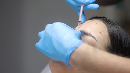 A cosmetologist gives a beauty injection to a woman's face in a cosmetology center, close-up....