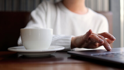 Close-up of hands of unrecognizable businesswoman typing on laptop keyboard while working online. The concept of remote work online, freelancing and successful business.