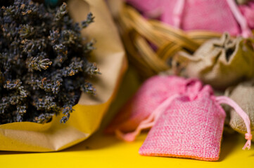 Dried lavender flowers and sachets on a yellow background.