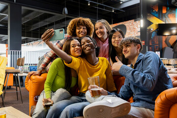 Naklejka premium Happy friends taking selfie photo at brewery restaurant - Group of multiracial people enjoying happy hour in arcade - Lifestyle concept with guys and girls hanging out