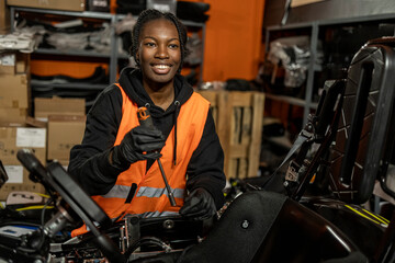 African American woman go kart mechanic repairing electric car in workshop