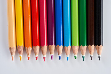 Many rainbow colored pencils on white