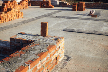 Bricks masonry with cement on concrete foundation, process of house building. Red bricks for laying...