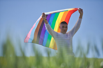 Non-binary person, young and South American, very makeup, waving a gay pride flag in the middle of...