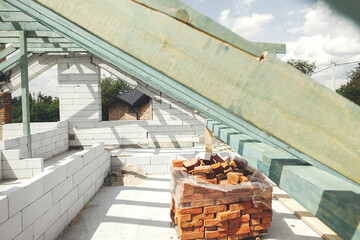 Wooden roof framing. Unfinished roof trusses and aerated concrete block walls, view in attic with...