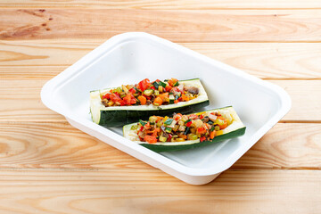 Zucchini stuffed with vegetables. Vegetarian food. Takeaway food. On a wooden background.