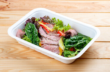Salad with roast beef sous-vide. Healthy food. Takeaway food.  On a wooden background.