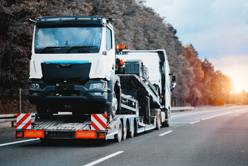 Towing truck with a brand-new commercial vehicle for cargo shipping. Emergency roadside assistance. Vehicle Mechanical Problem on the Road. Warranty case. Bill of Loading Manifest.	 - obrazy, fototapety, plakaty