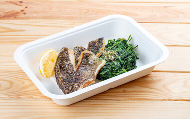Sea bass fillet with spinach. Healthy food. Takeaway food. On a wooden background.